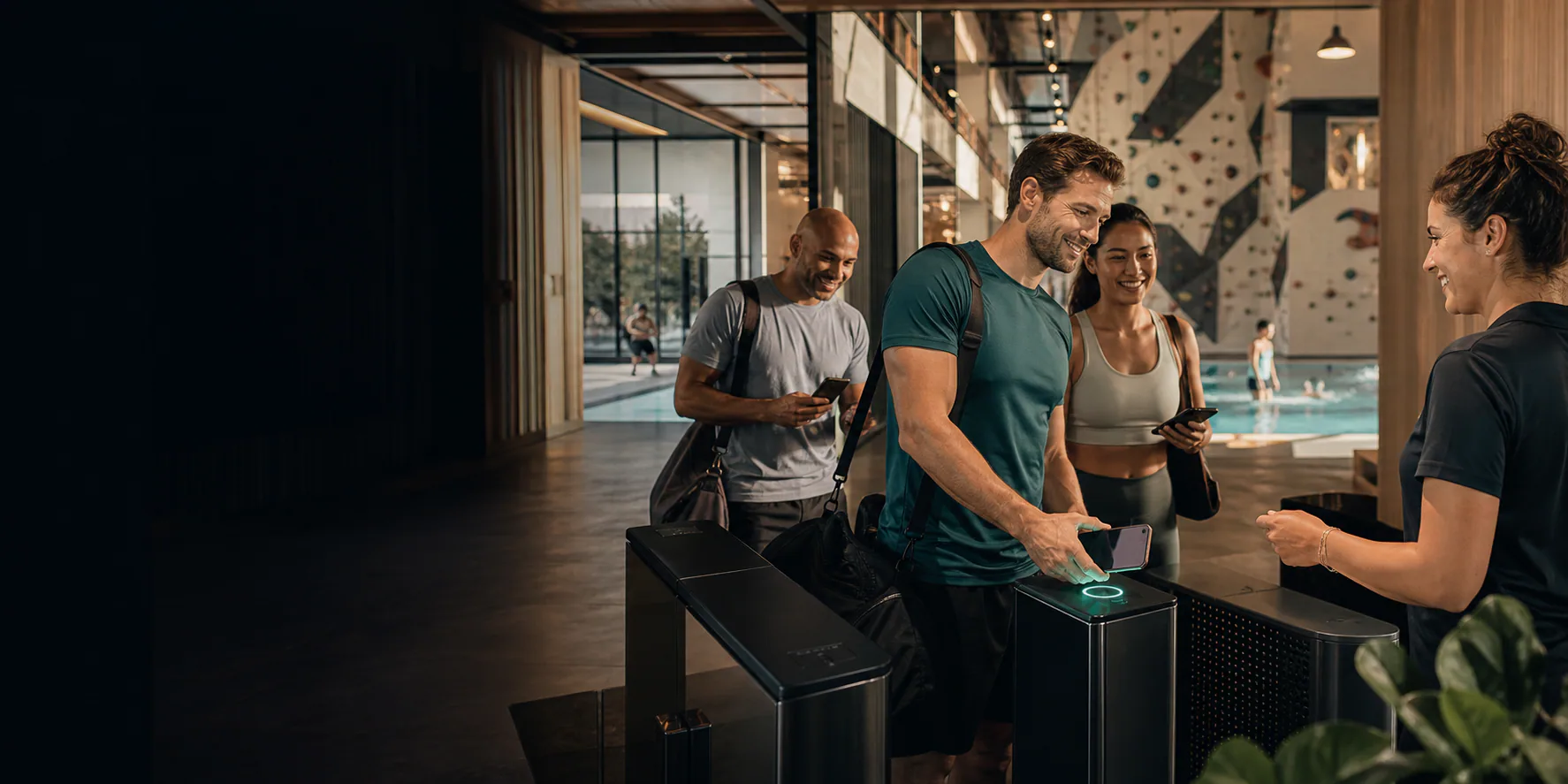 Gäste checken gut gelaunt per Smartphone in eine moderne Sport- und Freizeiteinrichtung ein